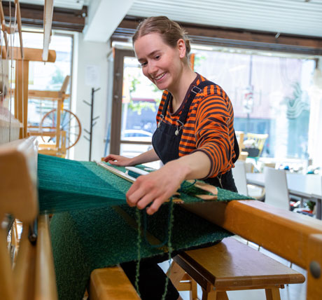 A young woman weaving with a loom.