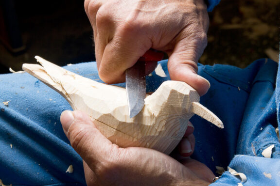 Man carving a wooden bird.